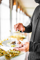 man hands take a snack and put it on plate. buffet in a restaurant