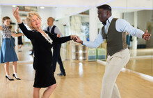 Elderly Woman Learning Ballroom Dancing In Pair In Dance Studio