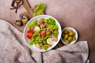 Wall Mural - Healthy tuna salad with fresh lettuce, cherry tomatoes, quail egg and olives in bowl