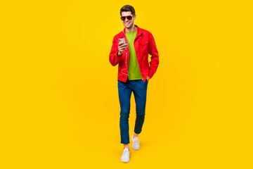 Wall Mural - Full body photo of nice brunet young guy go listen music wear glasses shirt trousers footwear isolated on yellow background