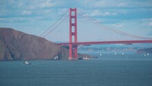 Wide Shot Showing End Of Golden Gate Bridge Hiding Behind Mountain In Summer - Boats Cruising On River Bay In San Francisco 