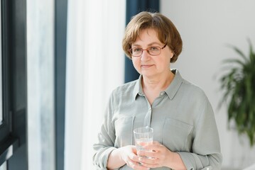 Wall Mural - Elderly woman holding glass of water. Concept of retirement