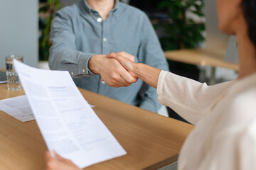 Wall Mural - Unrecognizable HR manager shaking hands with successful vacancy candidate after work interview at modern office