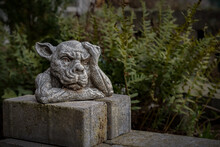 Closeup Of A Statue Of A Gargoyle Or A Gordon With Its Hand On The Head In A Park Or Garden