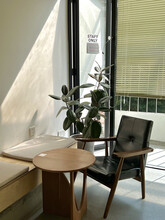 Vertical Shot Of A Cozy Corner In The Office With A Small Round Table And A Leather Chair