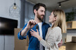 © Liubomir - Selected focus, married couple man and woman happy together, hugging, holding the keys to their new apartment, housewarming, close-up photo