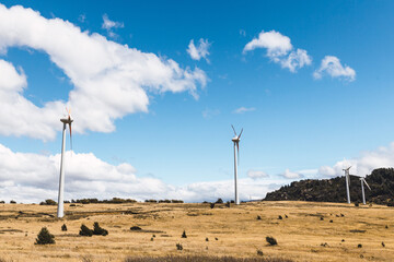 Natural view of windmills on vast dryland under a cloudy blue sky