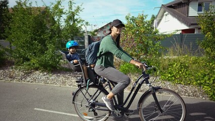 Wall Mural - Woman riding bicycle with toddler in back seat mother cyclist