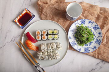 Canvas Print - Japanese sushi nigiri and rolls, wakame seaweed salad, soy sauce and chopsticks on a marble table