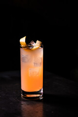 Poster - Beautiful shot of an orange cocktail on a black background