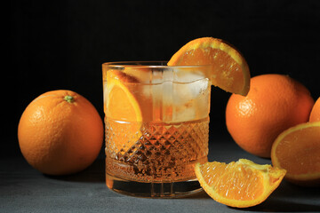 Sticker - Closeup shot of a spritz cocktail in a glass with oranges on a grey surface on a black background