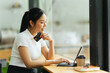 © PaeGAG - smiling woman paying online, using laptop, holding plastic credit card, sitting on coffee shop, Asian female shopping, making secure internet payment, browsing banking service.