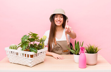 Wall Mural - hispanic pretty woman smiling proudly and confidently making number one. plants and gardering concept