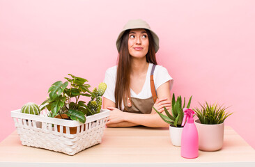 Wall Mural - hispanic pretty woman shrugging, feeling confused and uncertain. plants and gardering concept