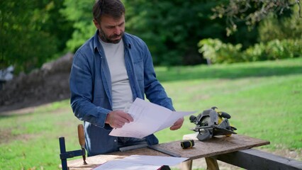 Wall Mural - Mature man engineer with blueprints of a house outdoors.