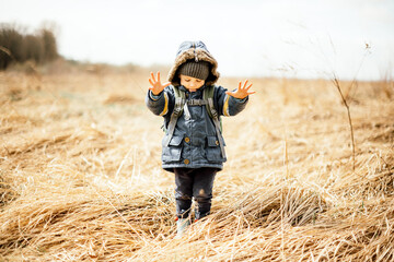 Wall Mural - Small kid in yellow dry grass field. Childhood with nature loving concept