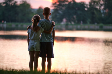 happy siblings hugging lovingly in summer park. young children brother and sister embracing each oth