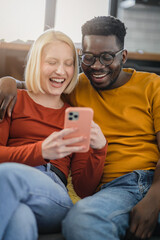 Happy multi-ethnic couple looking for something on a smartphone indoors