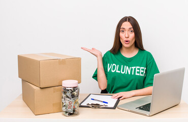 Poster - hispanic pretty woman looking surprised and shocked, with jaw dropped holding an object. donations volunteer