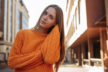 Pretty Young Blond Woman Posing In Orange Sweater With Long Sleeves On The Sunset Street 