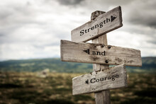 Strength And Courage Text Quote Written In Wooden Signpost Outdoors In Nature. Moody Theme Feeling.