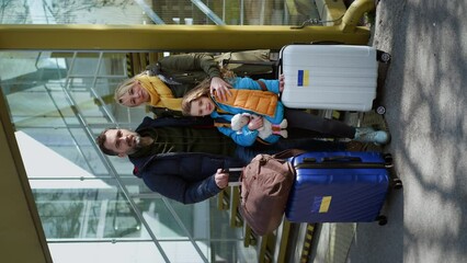 Wall Mural - Ukrainian refugee family with luggage at railway station hugging and saying goodbye, vertical footage.