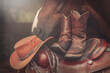 Ranch scene: Western boots and a cowboy hat on a western saddle in front of a horse