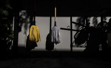Two Cloth Floor Mops Hanging From The Concrete Wall After Housekeeping For Dry By Sunlight. House Cleaning Concept Background, Selective Focus.