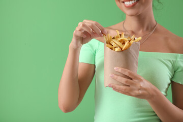 Canvas Print - Young African-American woman with french fries on green background