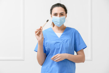 Wall Mural - Female dentist with activated charcoal tooth paste and brush on light background