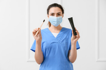 Wall Mural - Female dentist with activated charcoal tooth paste and brush on light background