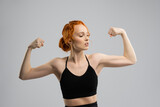 Positive young sportswoman happy look at biceps - studio shot