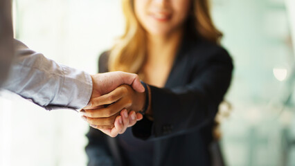 Portrait young Asian woman interviewer and interviewee shaking hands for a job interview .Business people handshake in modern office. Greeting deal concept