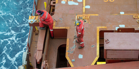 Wall Mural - Seaman ship crew priming and derusting vessel deck for upcoming painting.