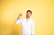 © Odua Images - smiling asian young man with finger pointing up on isolated background