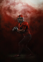 Red sky. Creative portrait of young man, american football player at stadium in motion on smoked background. Sport, challenge, goals, activity, sportlife concept.