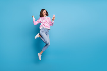 Canvas Print - Photo of charming lucky lady dressed pink pullover jumping high typing modern device empty space isolated blue color background