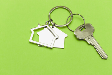 The concept of mortgage and rental housing and real estate. Mortgage credit lending. Keychain in the shape of a house with a key on a light green background.