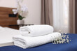 © New Africa - Stack of clean towels with flowers on bed in hotel room