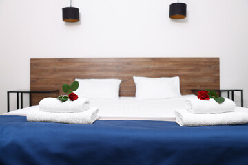 Sticker - Clean folded towels with flowers on bed in hotel room