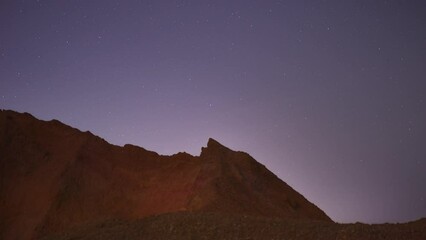 Wall Mural - 4k time-lapse video motion of night sky with circular star trails over the rock formations mountains