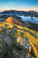 Stunning Early Morning Sunlight From The Top Of Catbells In The Lake District, With A View To The Lake Below And The Distant Fells Of Blencathra And Skiddaw