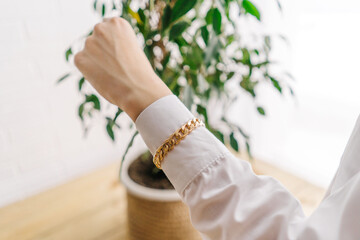 Wall Mural - Golden bijouterie bracelet from chain on woman hand.