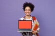 Young smiling happy girl woman of African American ethnicity teen student in shirt backpack hold use work on laptop pc computer with blank screen workspace area isolated on plain purple background