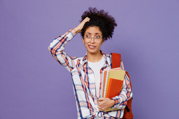 Wall Mural - Young sad girl woman of African American ethnicity teen student in shirt backpack scratch hold head look aside isolated on plain purple background. Education in high school university college concept.