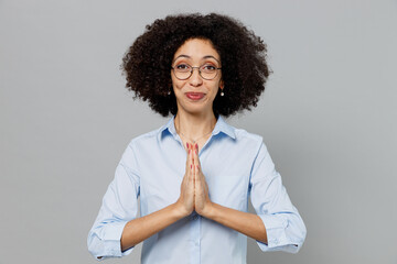 Wall Mural - Young employee business corporate lawyer woman of African American ethnicity in classic formal shirt work in office hand folded in prayer gesture beg about something isolated on grey color background