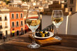 © barmalini - Two glasses of Spanish dry rueda white wine served with olives on roof terrace with view on old part of Andalusian town Granada, Spain