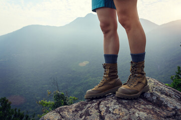 Wall Mural - suceesful woman hiker legs stand on mountain peak cliff edge