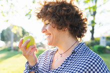 Cheerful Woman With Apple In Park
