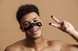 © Drobot Dean - Shirtless man with cosmetic mask smiling and gesturing at camera
